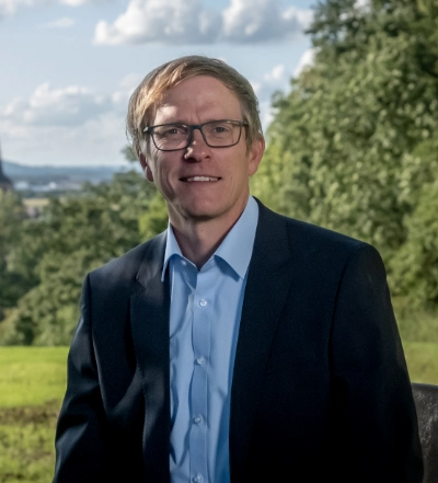 Two young professionals working together at a desk with multiple laptops and a tablet