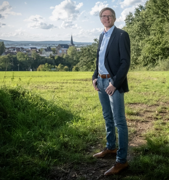 A group of four professionals, two men and two women, are gathered around a conference table reviewing printed charts and documents.