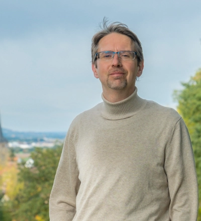 A group of four diverse professionals having a collaborative discussion around a desk with documents, a tablet, and a laptop.