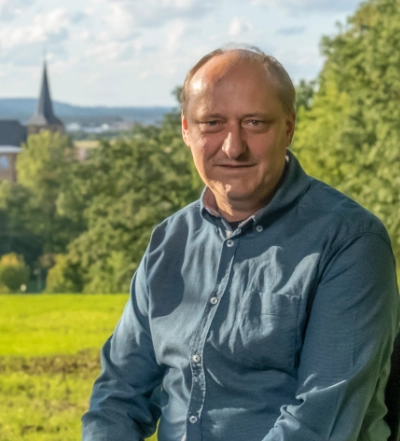 A group of four diverse professionals having a collaborative discussion around a desk with documents, a tablet, and a laptop.