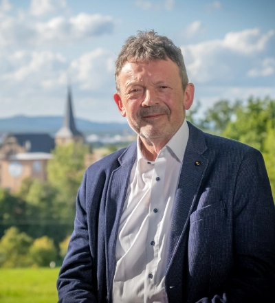 A group of four diverse professionals having a collaborative discussion around a desk with documents, a tablet, and a laptop.